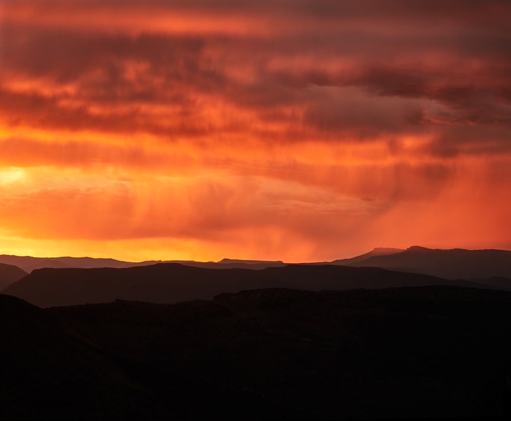 the sun is setting over a mountain range