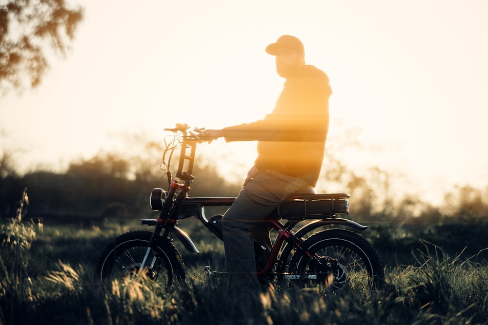 a man standing next to a bike in a field