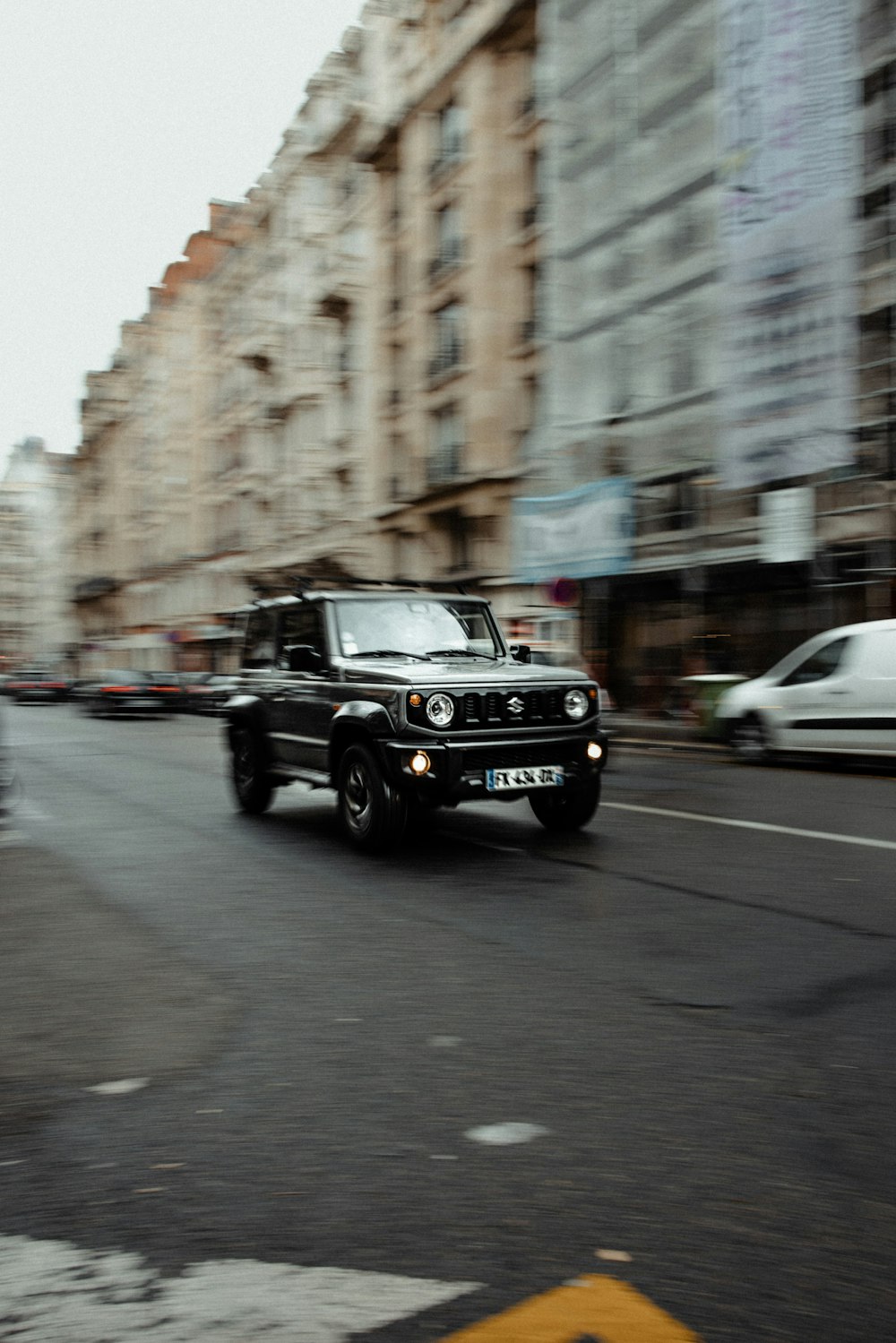 a black jeep driving down a street next to tall buildings