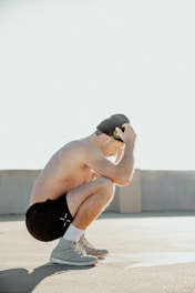 a man squatting on a skateboard in a parking lot