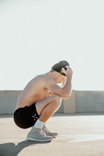 a man squatting on a skateboard in a parking lot