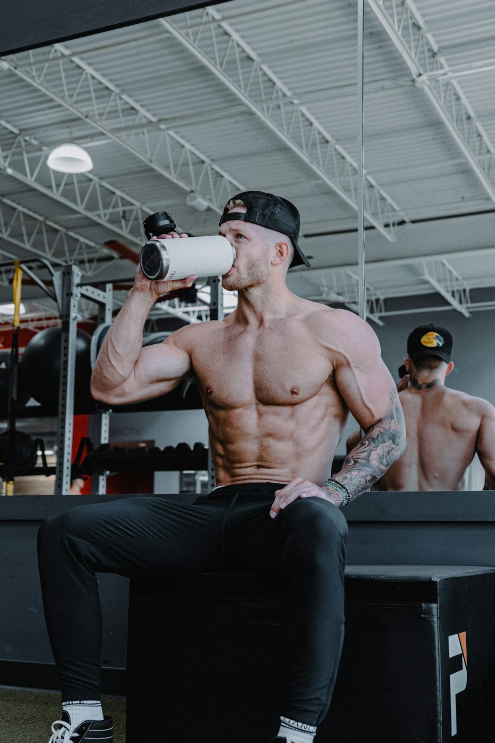 a shirtless man drinking from a white cup