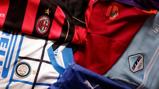 A collection of football jerseys from various Italian clubs, showcasing their distinct designs and colors. These jerseys feature prominent club logos and a variety of patterns, highlighting the unique identity of each team.