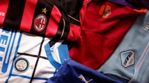 A collection of football jerseys from various Italian clubs, showcasing their distinct designs and colors. These jerseys feature prominent club logos and a variety of patterns, highlighting the unique identity of each team.