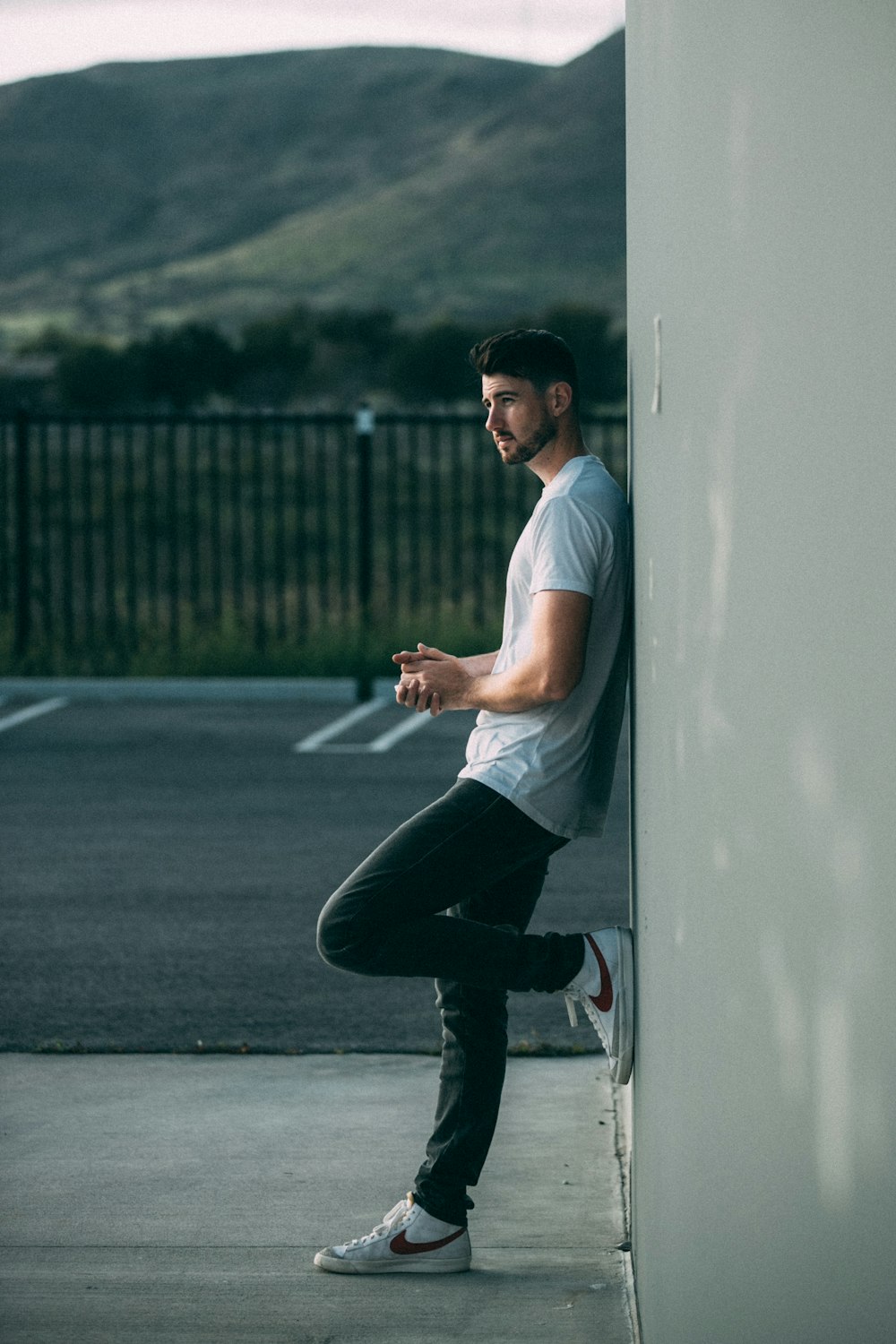 a man leaning against a wall and looking at his cell phone