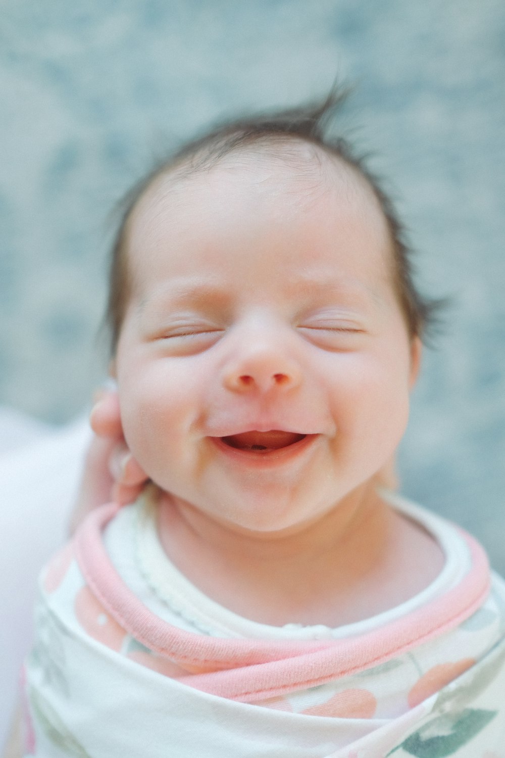 Eine Nahaufnahme eines Babys, das mit geschlossenen Augen lächelt