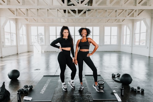 Two smiling gym members standing together after a workout in a bright fitness studio