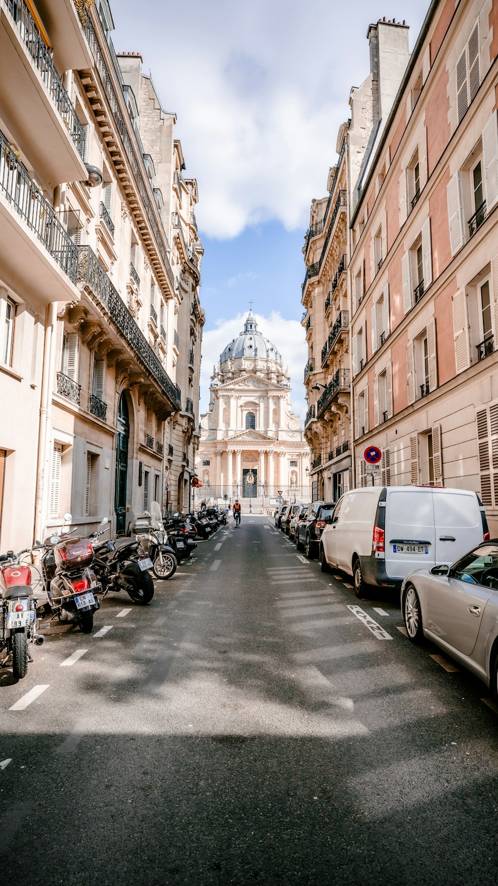 Une rue bordée de voitures et de motos garées