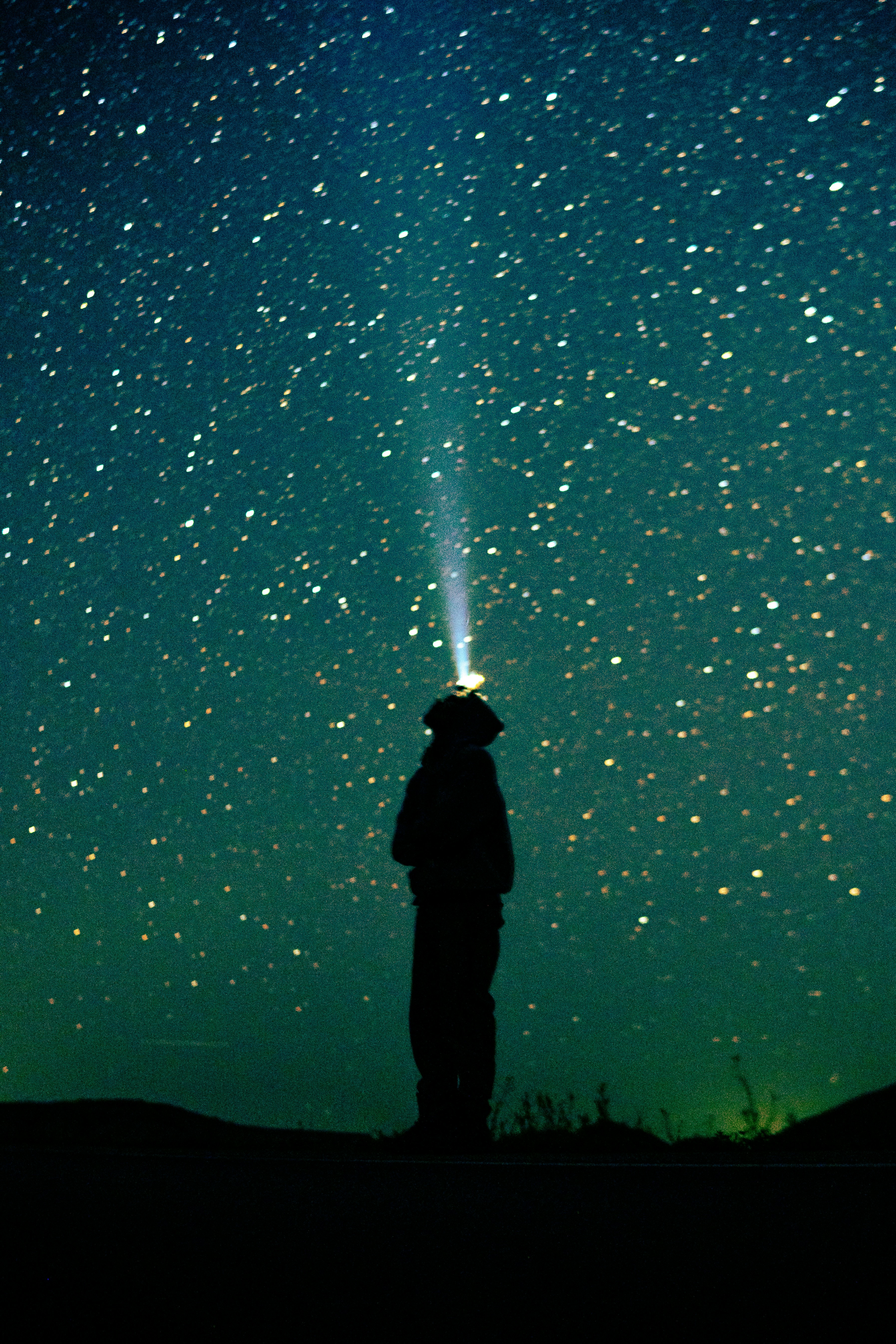 a man standing on top of a hill under a sky filled with stars