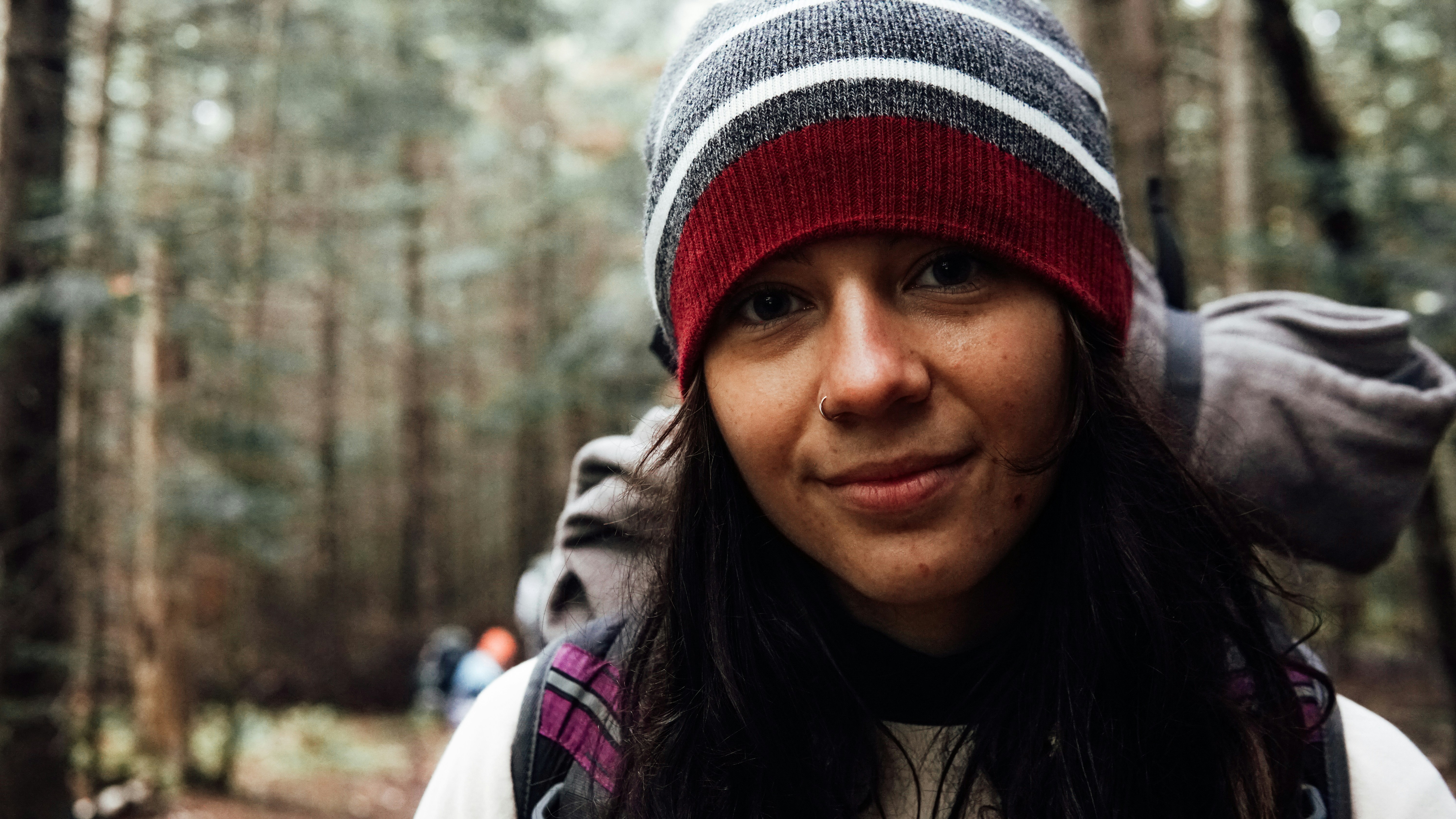 a woman wearing a red and gray hat in the woods