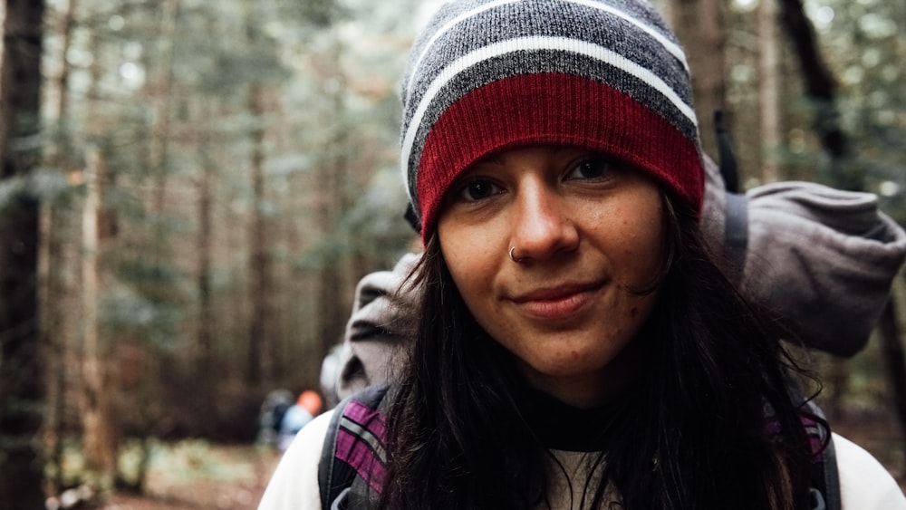 a woman wearing a red and gray hat in the woods
