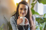 Smiling woman holding a personalized mug with a custom design in a cozy home setting.