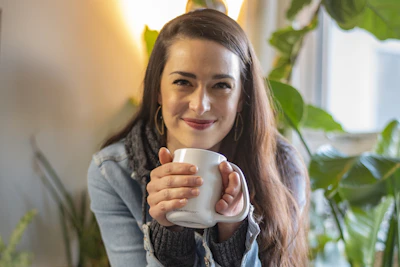 Smiling woman holding a personalized mug with a custom design in a cozy home setting.