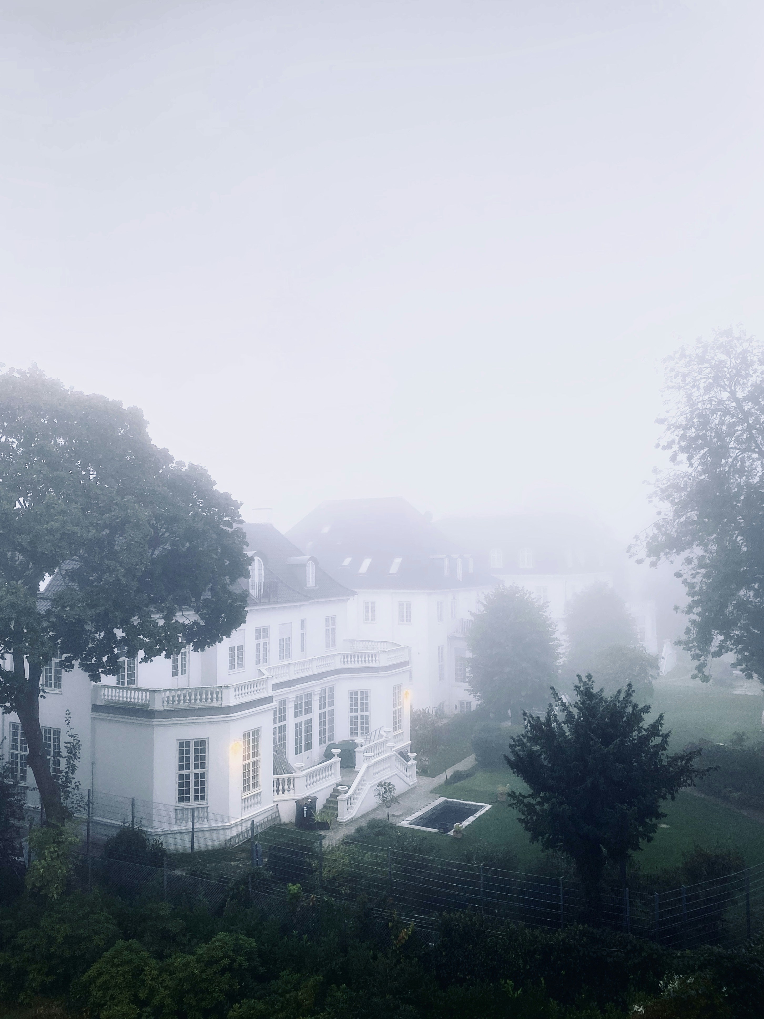 A white villa surrounded by a heavy mist