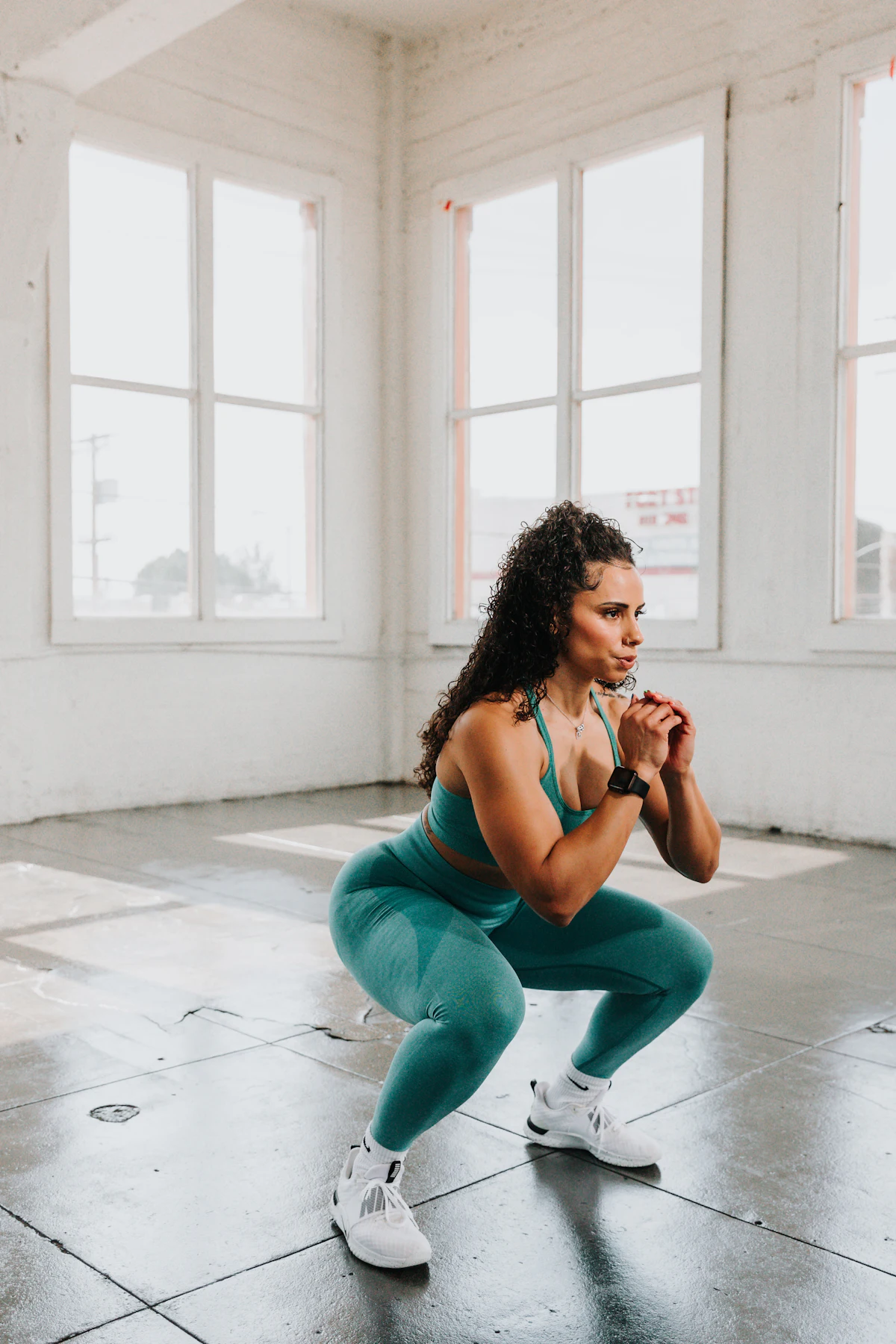Wanita berolahraga melakukan gerakan squat di lantai gym sebagai simulasi explosive power yang dibutuhkan untuk frog jump Primal Movement