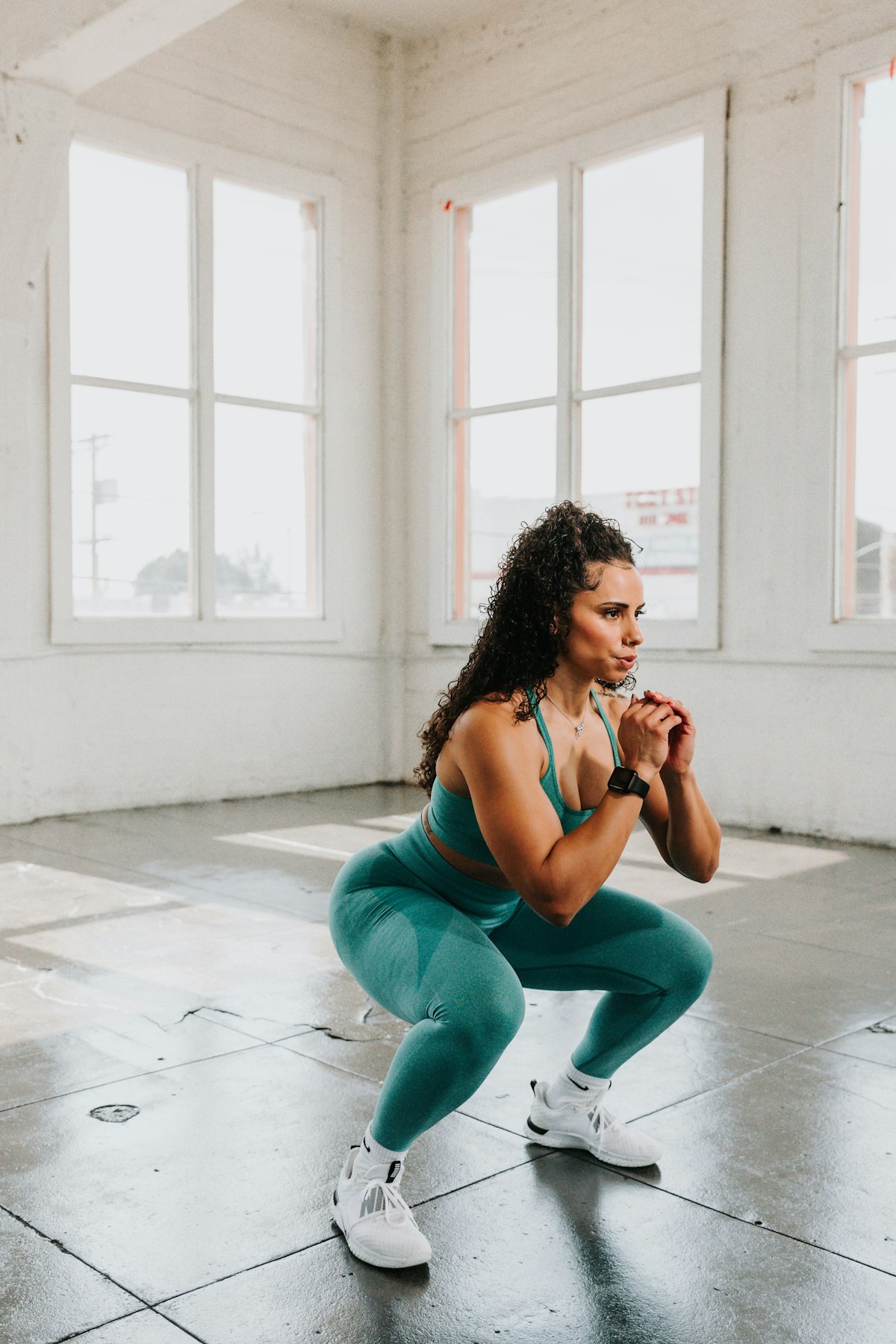 Wanita berolahraga melakukan gerakan squat di lantai gym sebagai simulasi explosive power yang dibutuhkan untuk frog jump Primal Movement