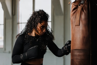 a woman in a black top and black gloves near a punching bag