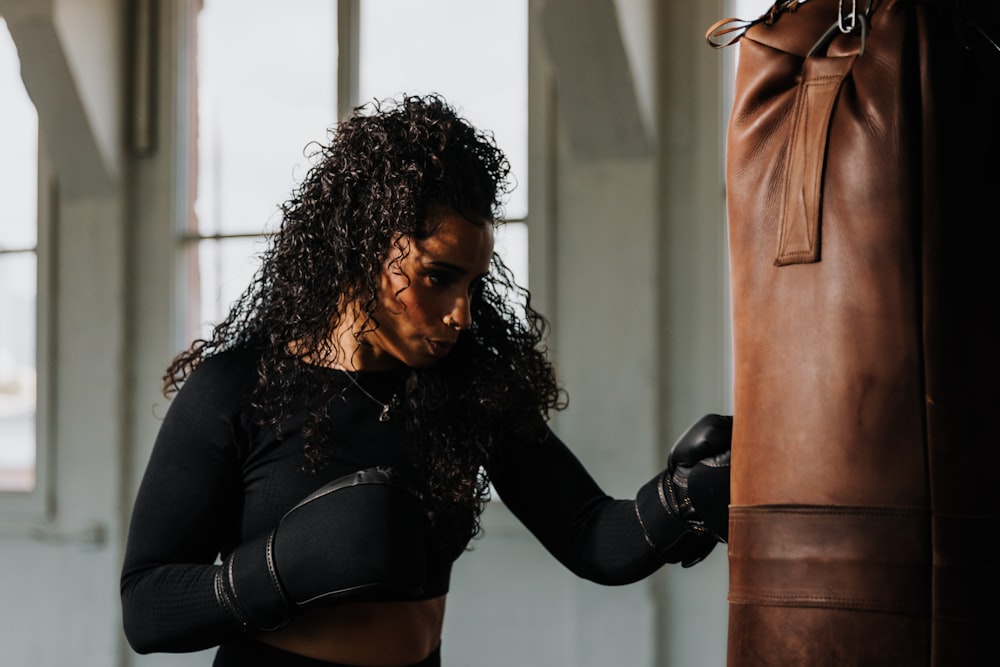 a woman in a black top and black gloves near a punching bag