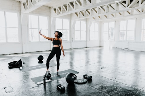 A warm photo of Tayná coaching a mother during a fitness session in a bright, welcoming studio.