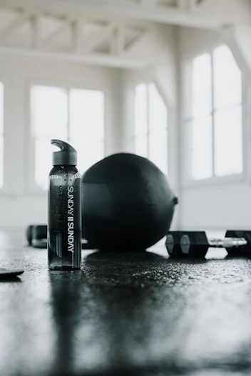 A water bottle with workout equipment in the back