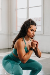 a woman squatting on the ground with her hands clasped
