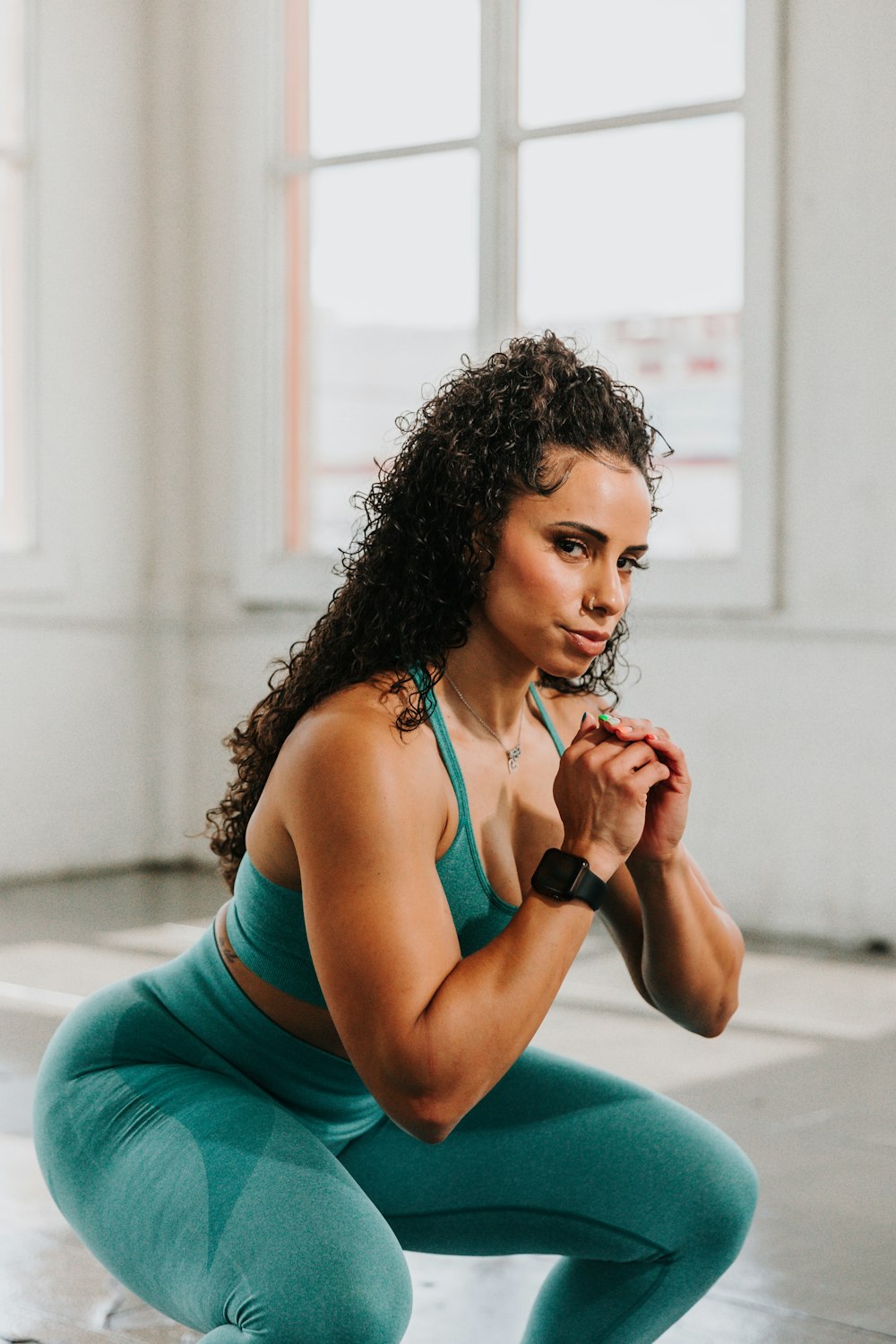 a woman squatting on the ground with her hands clasped