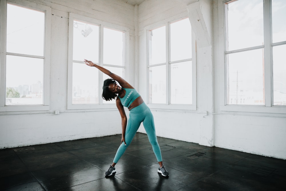 a woman in a blue sports bra top and leggings doing a yoga pose