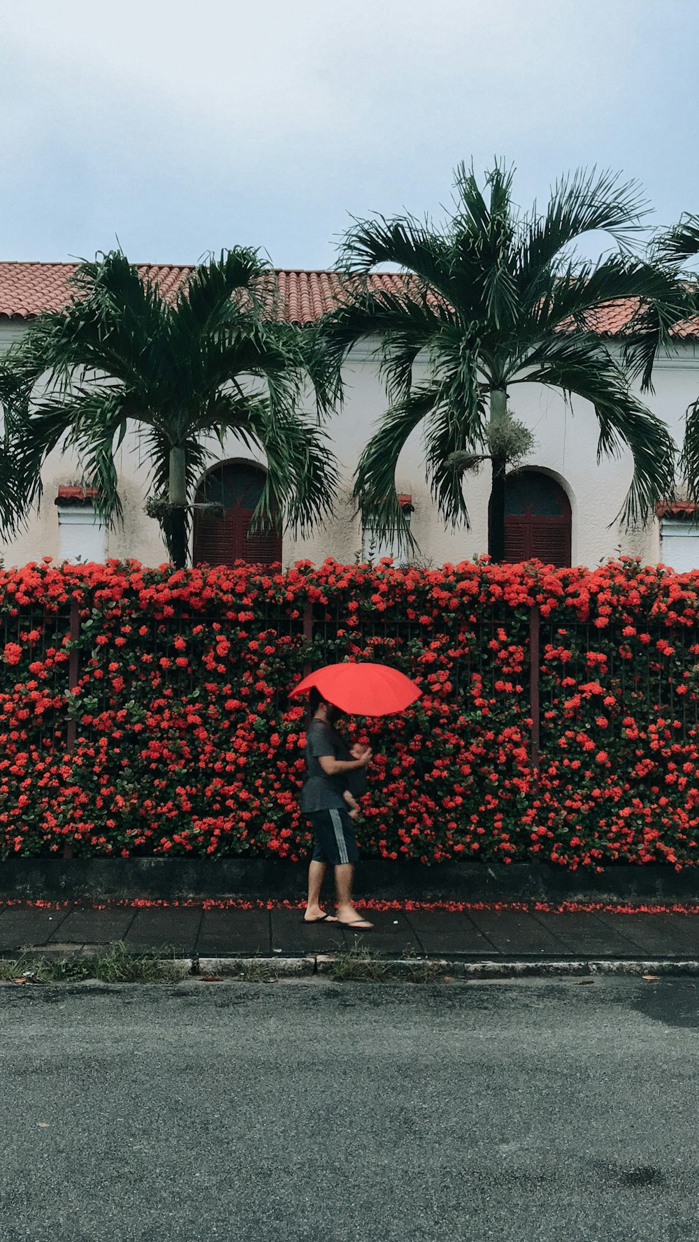 a woman walking down a street holding a red umbrella