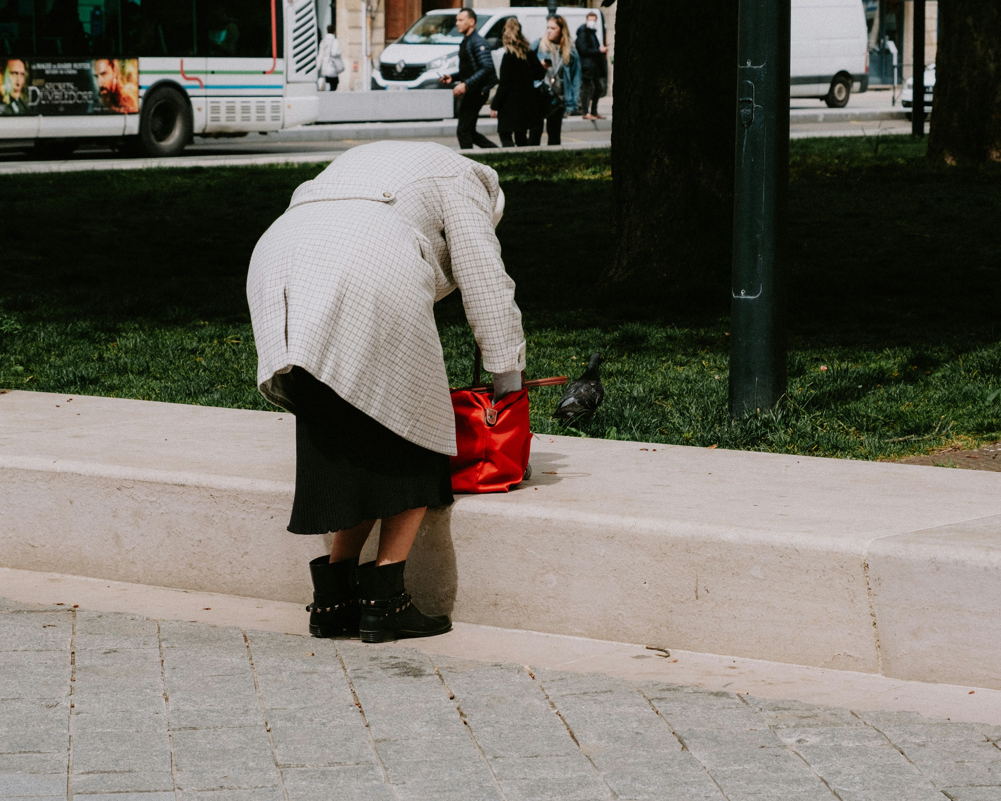 a woman leaning on a wall with a red purse