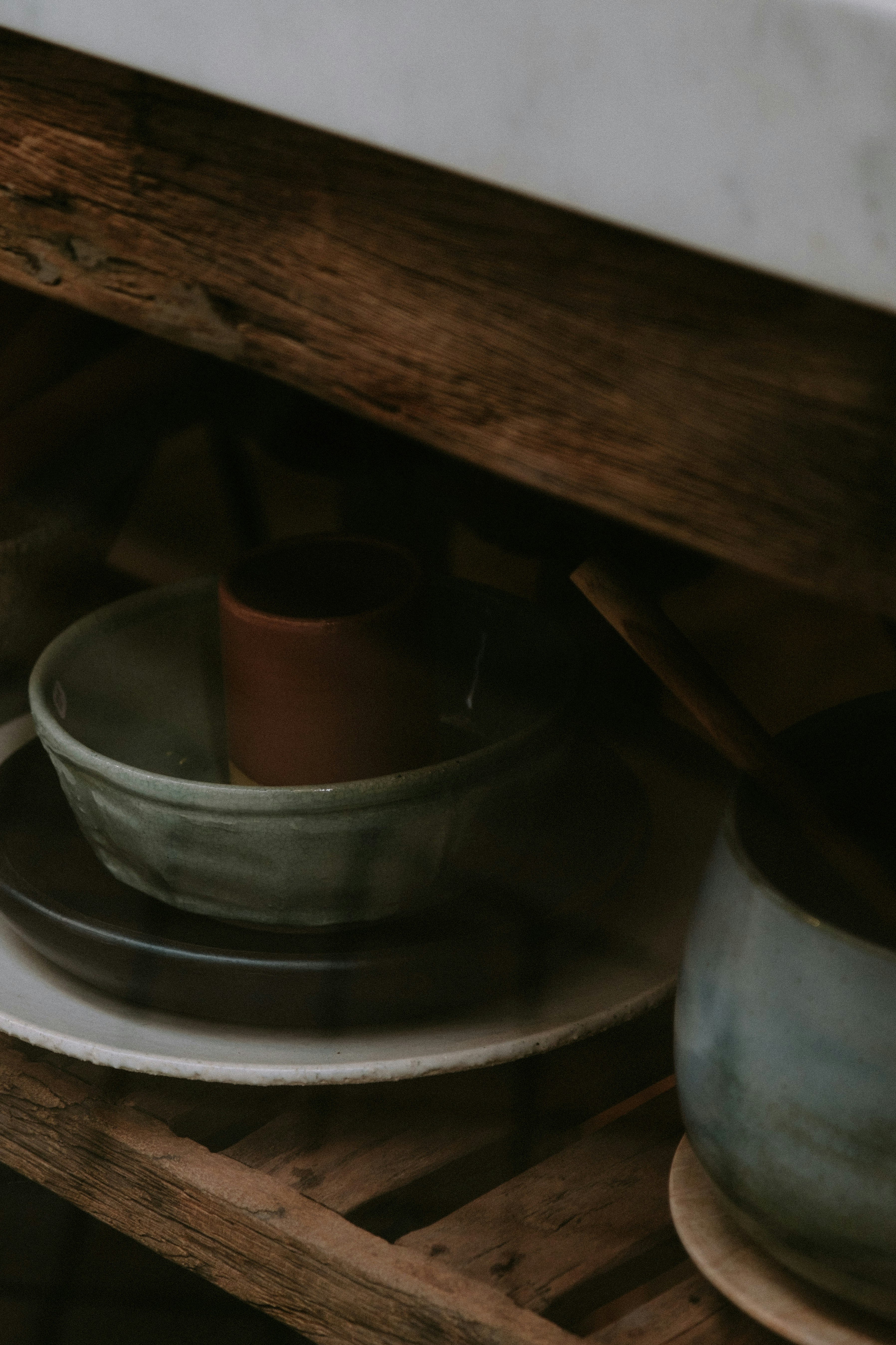 Artisan ceramic bowls and handcrafted pottery on wooden shelf, warm natural light, earthy tones