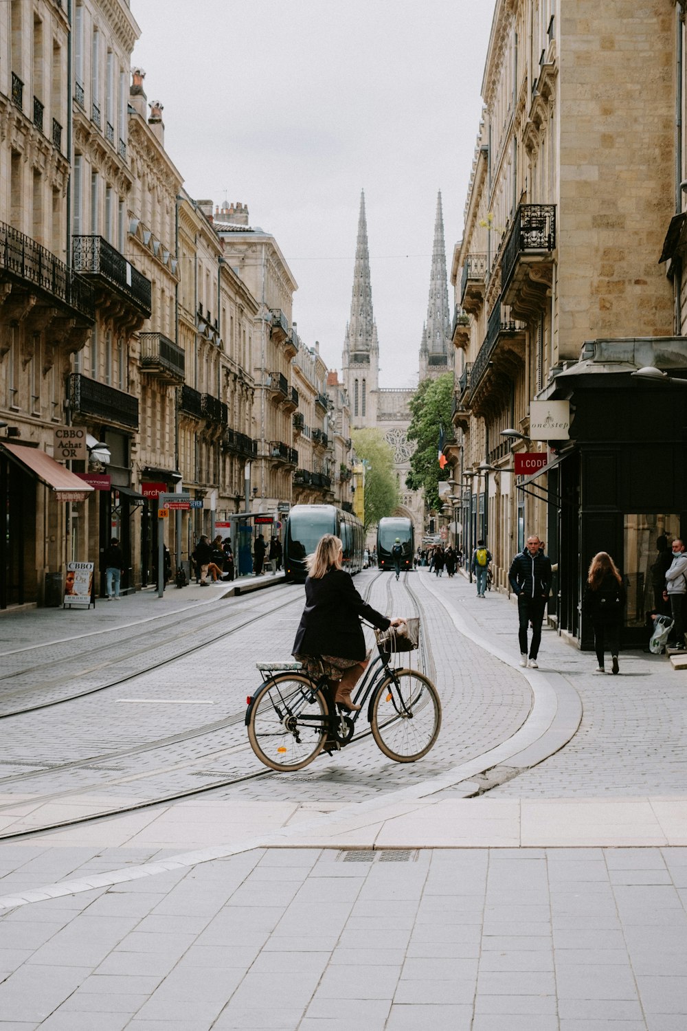 a woman riding a bike down a street next to tall buildings