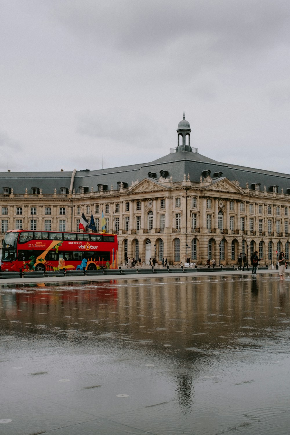 a red double decker bus parked in front of a large building