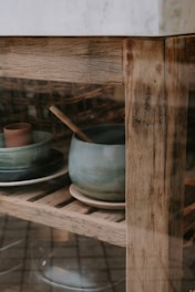 Display of handcrafted ceramic mugs on a rustic shelf in natural light.