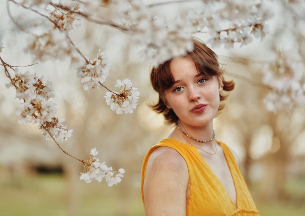 a woman in a yellow dress standing in front of a tree