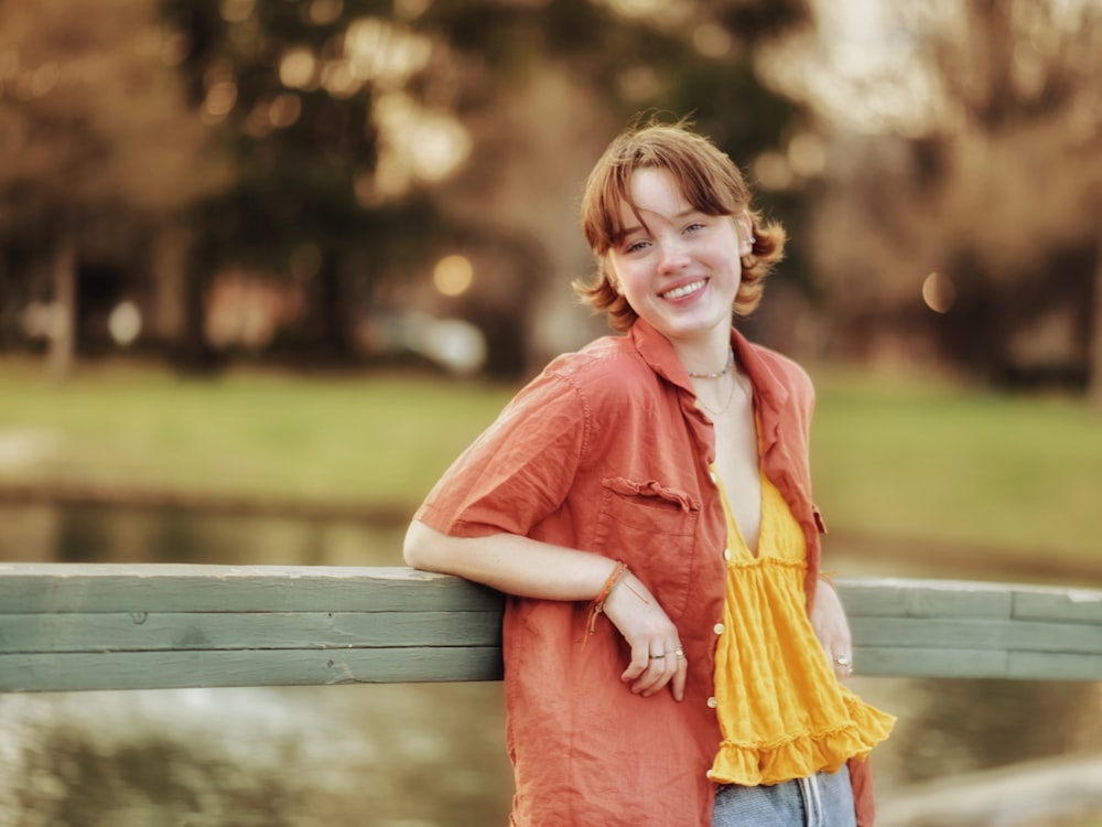 a young girl leaning on a fence smiling