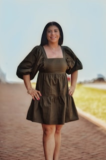 a woman in a green dress standing on a brick walkway