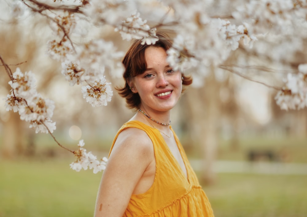 a woman in a yellow dress standing under a tree