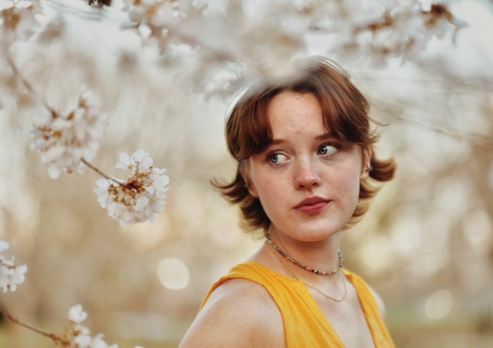 a woman standing in front of a tree with white flowers