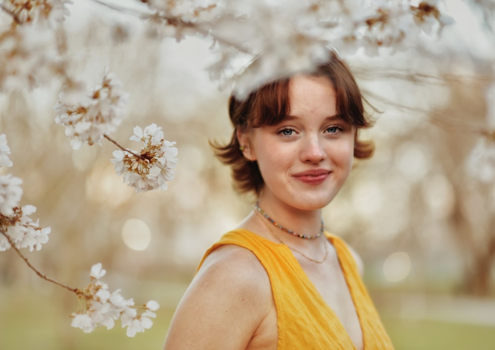 a woman in a yellow dress standing in front of a tree