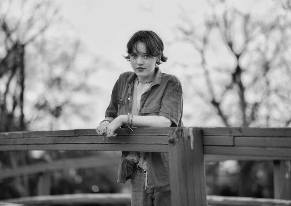 a young woman leaning on a wooden fence