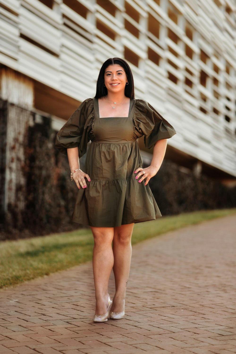 a woman in a green dress standing on a brick walkway