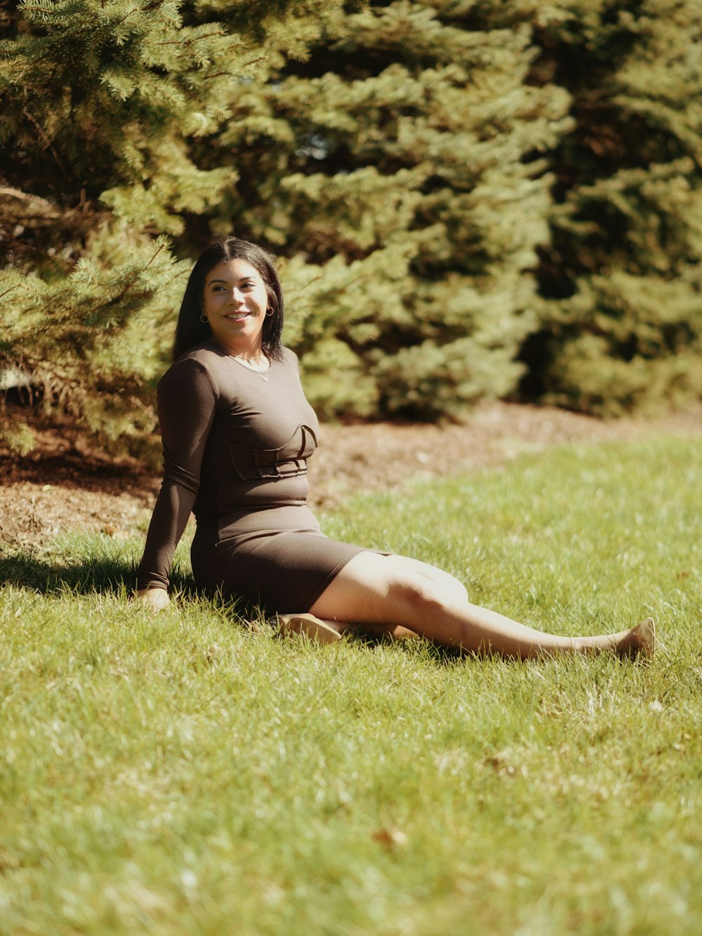 a woman in a brown dress sitting in the grass