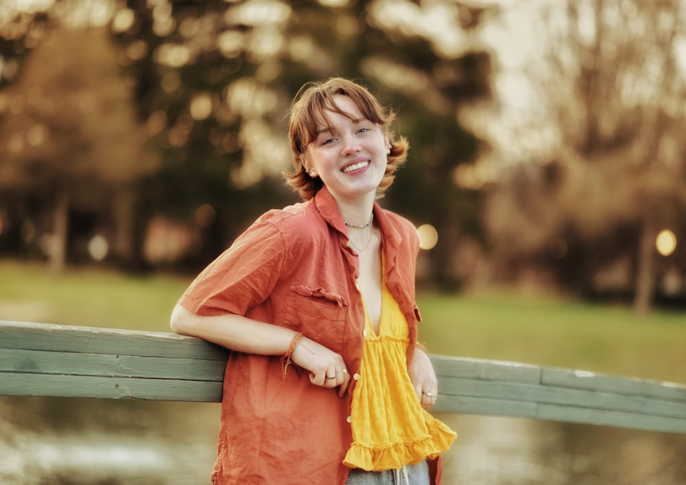 a young woman leaning on a wooden fence