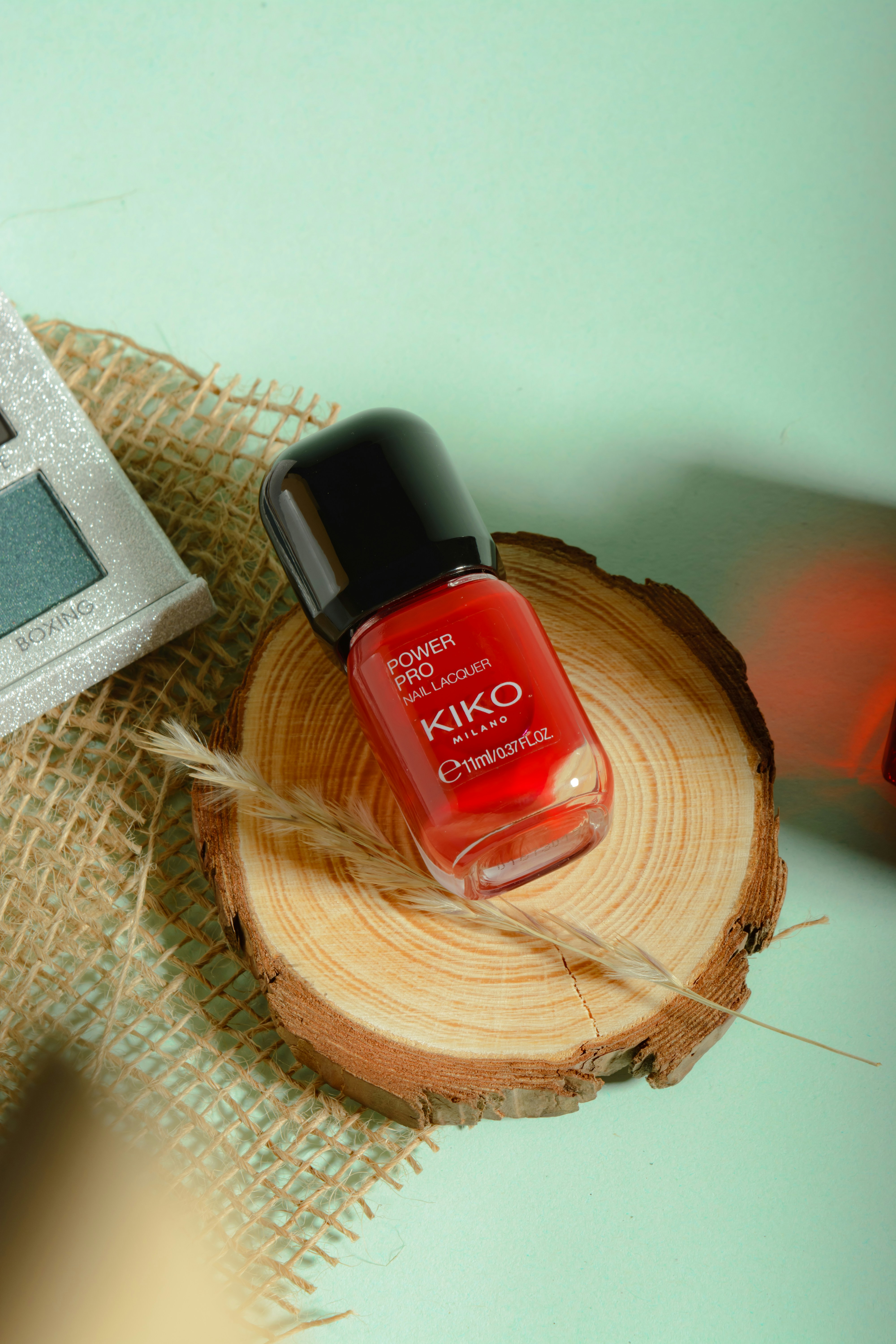 a red nail polish sitting on top of a piece of wood