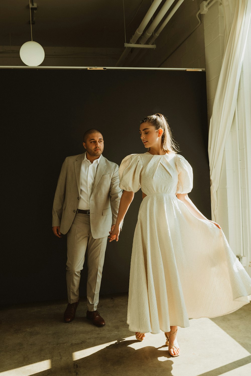 a woman in a white dress standing next to a man in a suit