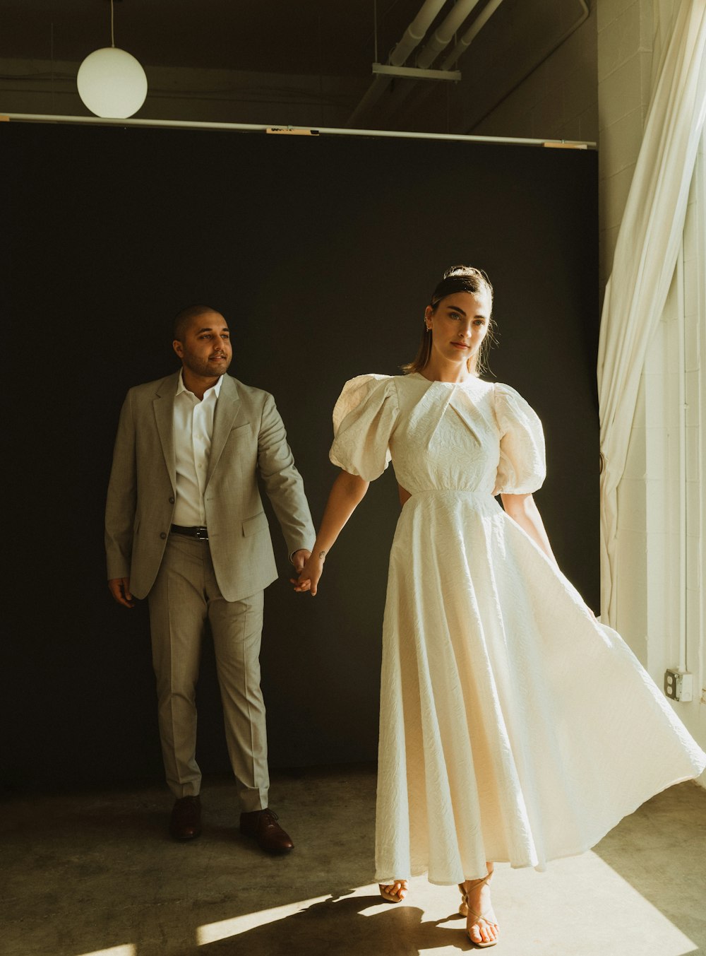 a woman in a white dress standing next to a man in a suit