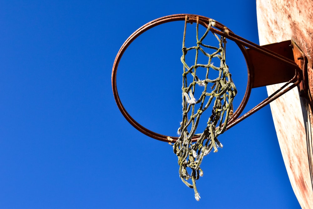a basketball going through a hoop with a blue sky in the background