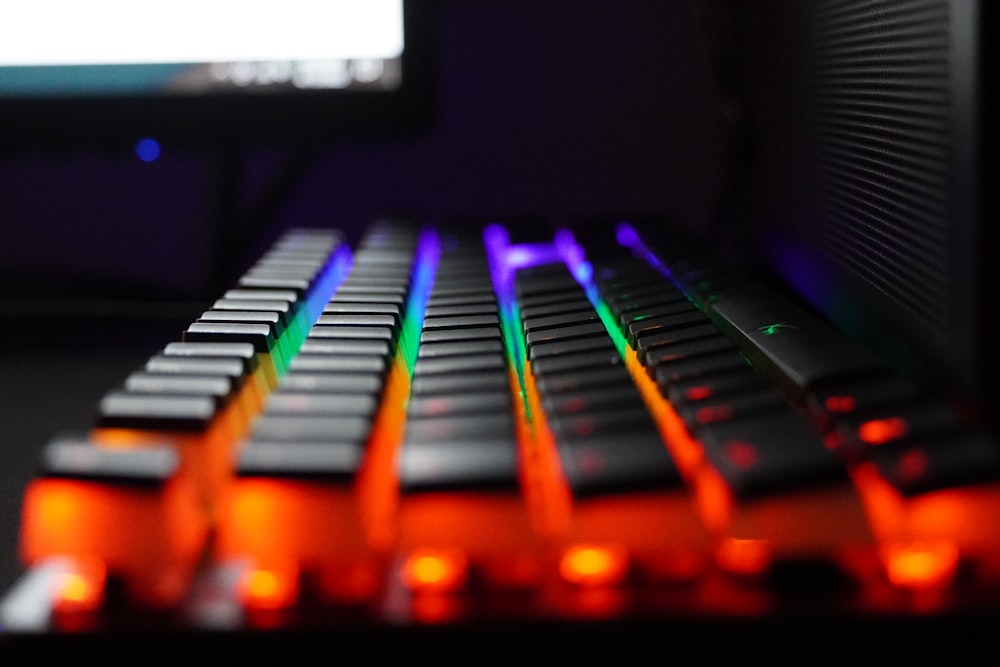 a close up of a keyboard with a monitor in the background