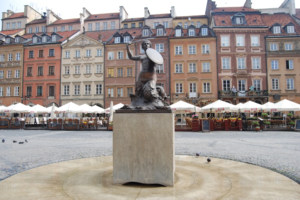 a statue of a woman holding a surfboard in front of a building