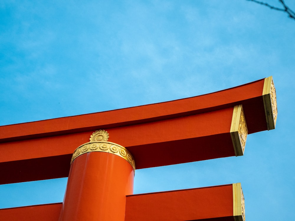 a tall red structure with gold trim against a blue sky